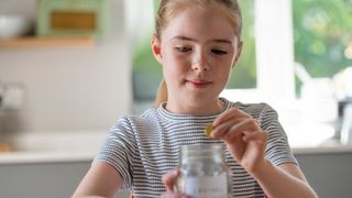 Young girl saving money in jar