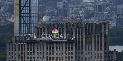 Comcast corporate logo sign on top of Rockefeller Center building in NYC..