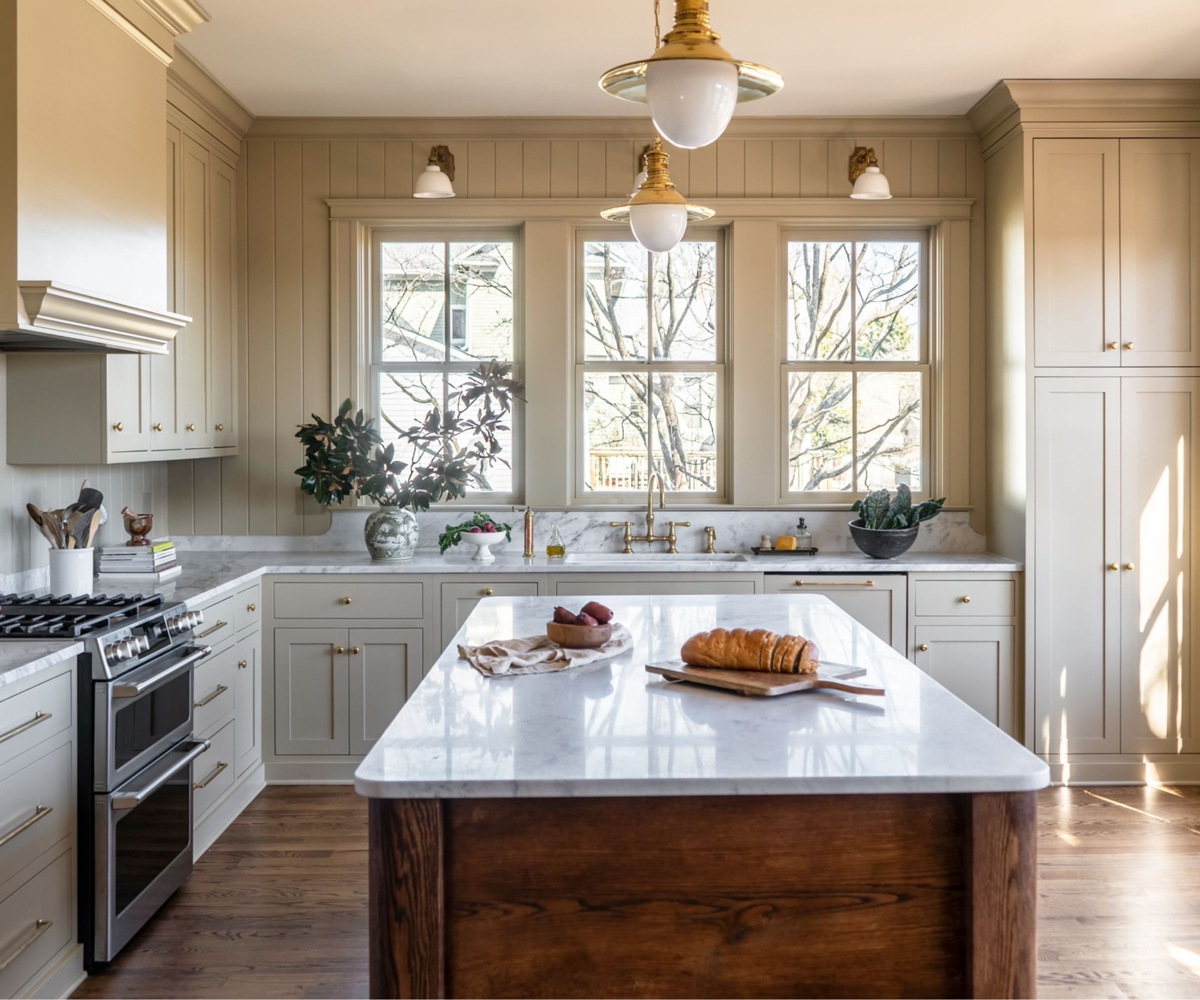 An L-shaped kitchen with a large wooden island and a sink placed beneath the window