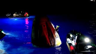 a white capsule floats in the ocean surrounded by boats