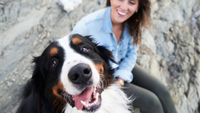 Dog looking happily at the camera with owner smiling behind them