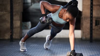 Woman performing plank with dumbbell raises