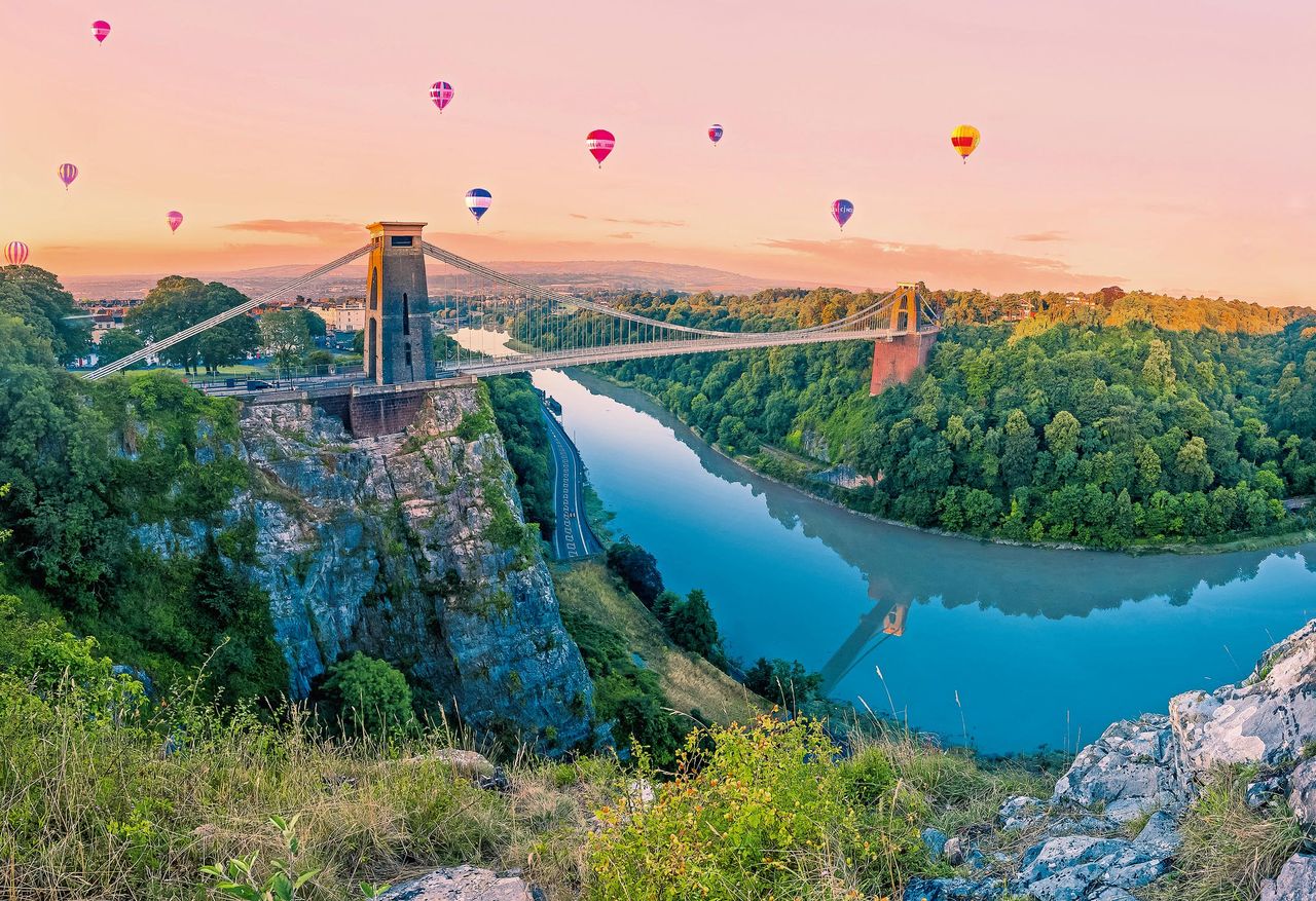 What a way to travel... Hot Air Balloons drift towards Clifton Suspension Bridge in Bristol at sunrise.