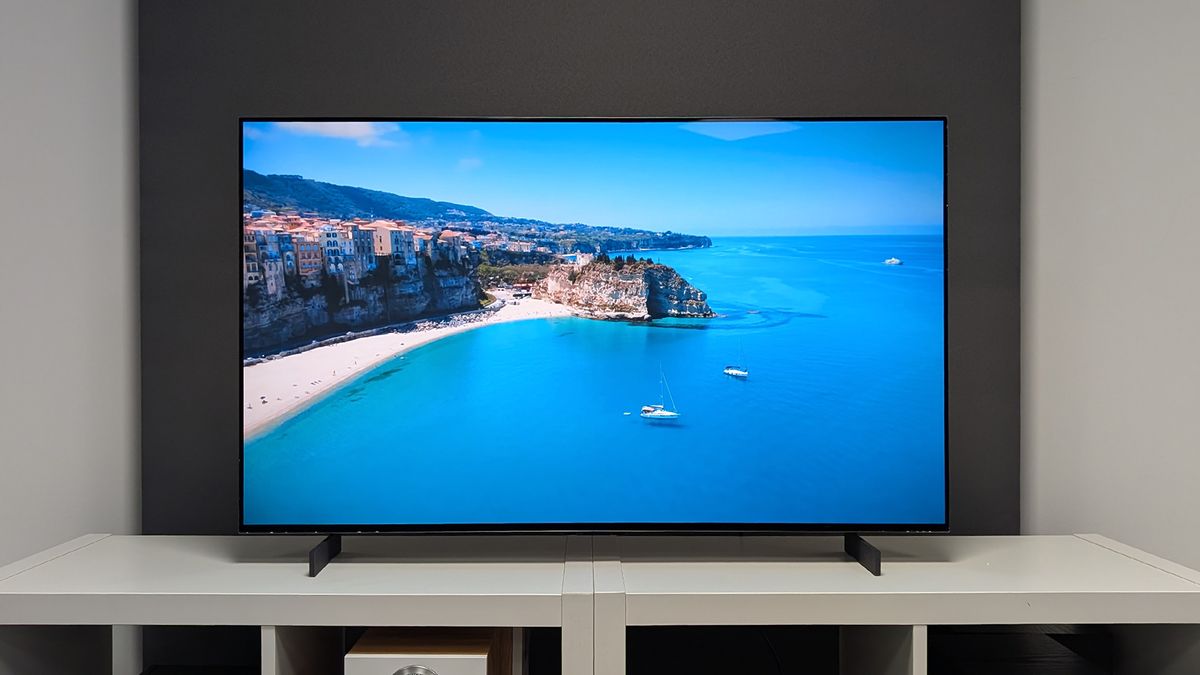 The LG C5 42-inch OLED TV seen straight-on on a TV cabinet. On screen is a Mediterranean seaside town with a beach and the sea. This is our pick for best 42-inch TV.