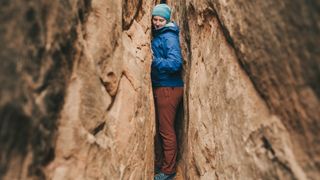 A woman squeezes through a narrow slot canyon