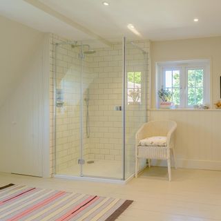 bathroom with white wall and shower and wooden floor and white chair