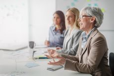 An older female worker makes a comment at an office meeting.