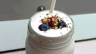 The Banana Flax Smoothie served in a glass jar topped with seeds and berries