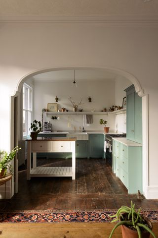 pale green l shape kitchen with pink butchers block island