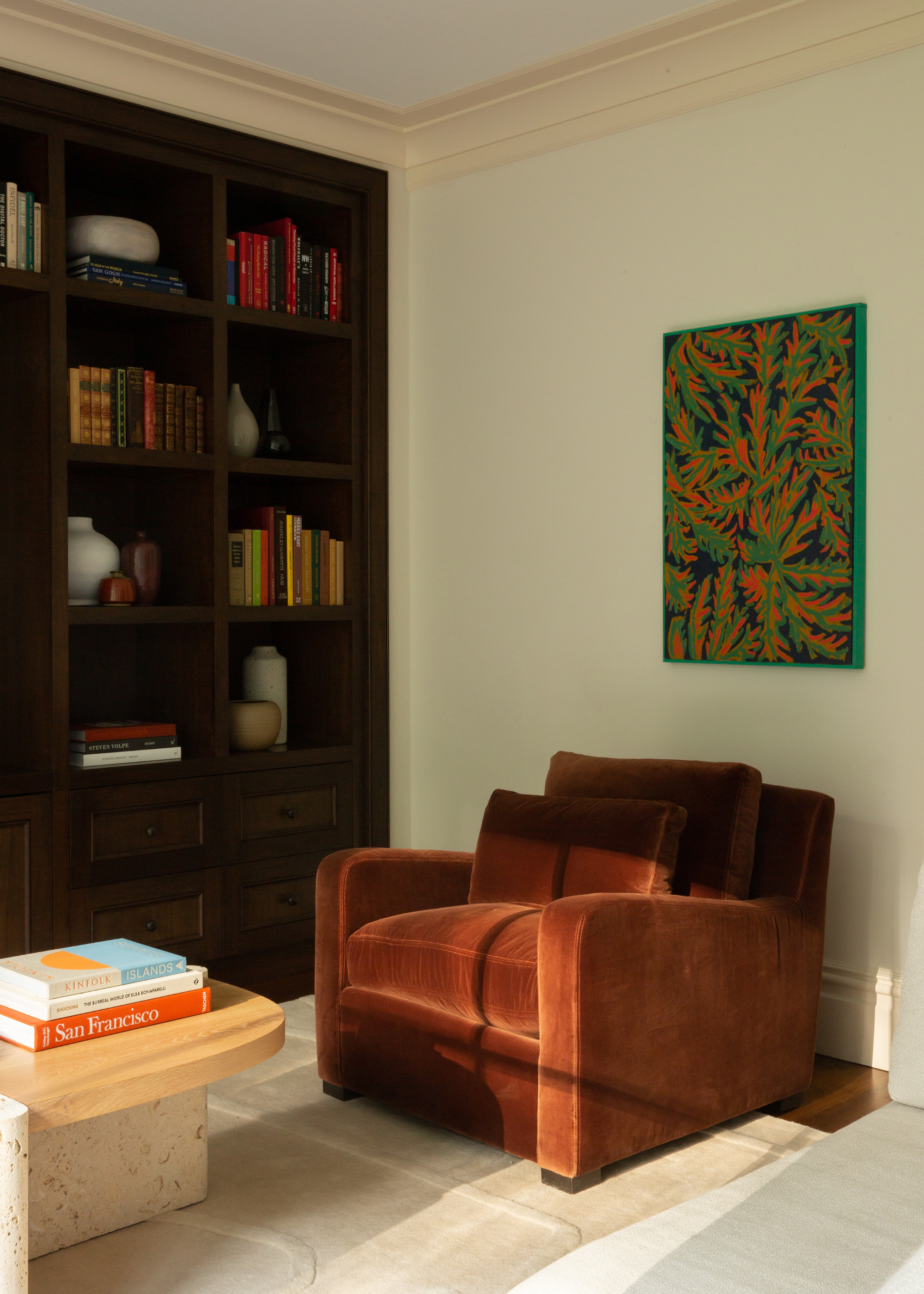 A wood bookshelf beside a plush sofa chair in a living room area