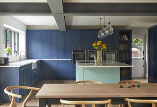 blue kitchen units and island with modern dining area