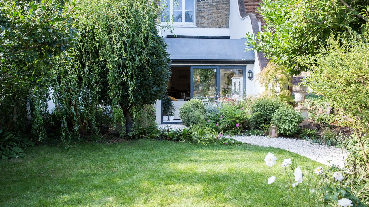 A garden with a green lawn at the back of a town house