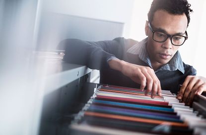 A man searches through a file cabinet drawer