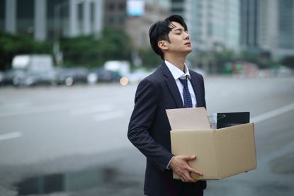 businessman carrying box of personal items.