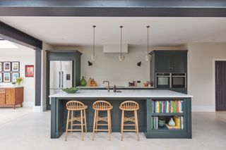 Kitchen with green painted cabinets, island, neutral walls and floor