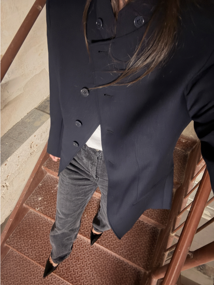 Rachel Whitehouse walking down stairs wearing navy blazy, grey jeans, black heels