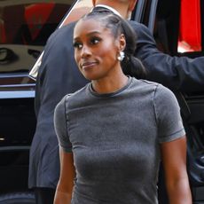 Issa Rae wearing a gray T-shirt, gray pants, and white Adidas samba sneakers