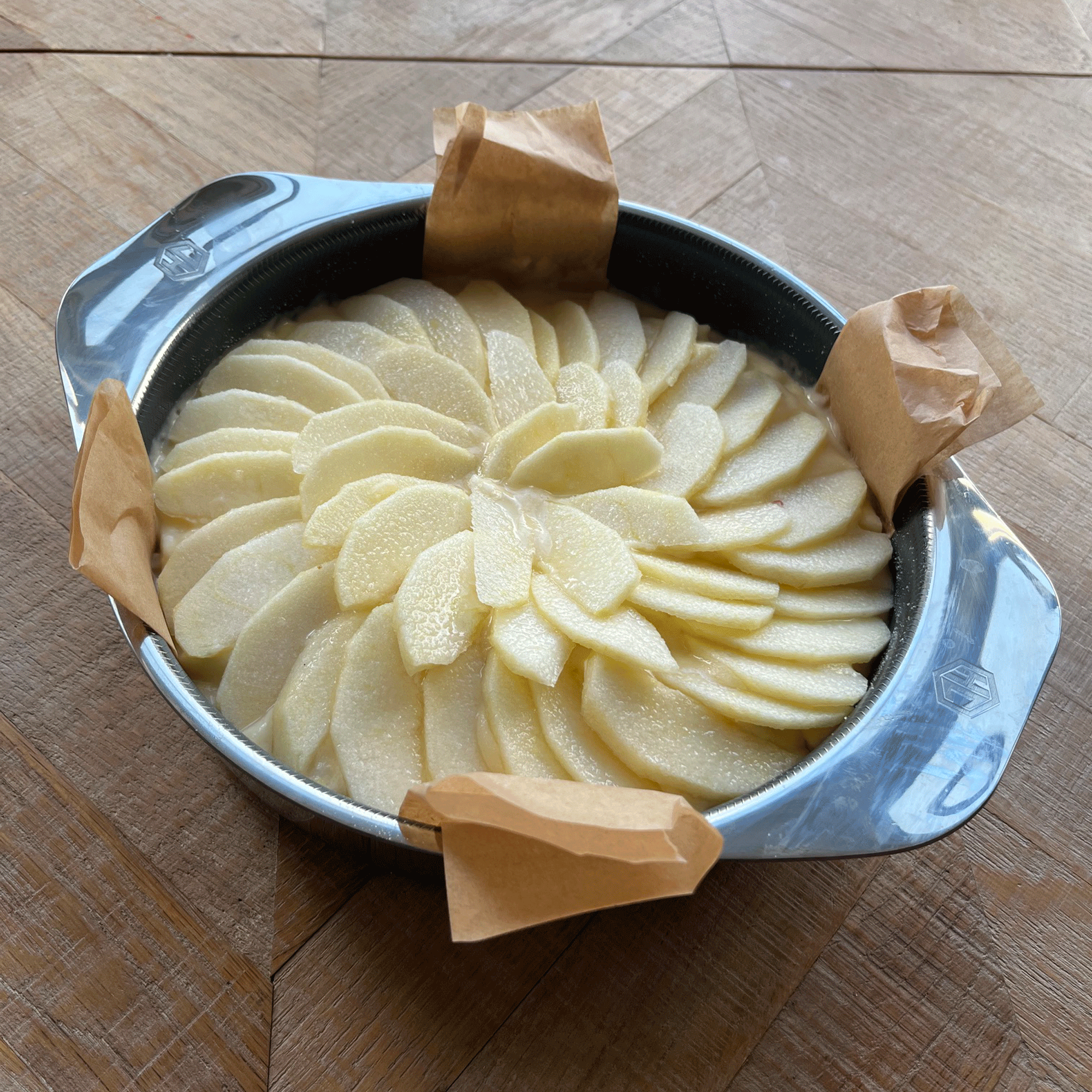 an unbaked apple cake in a HexClad baking tin on a wooden surface