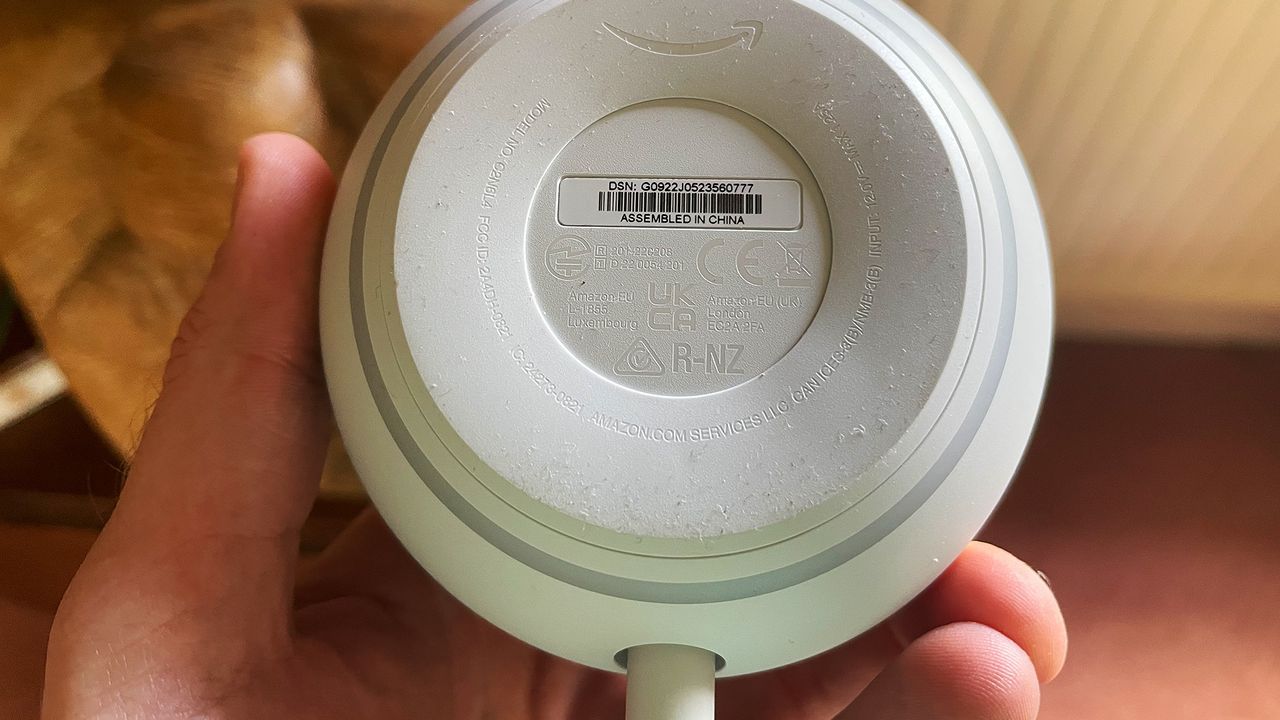 The bottom of an Amazon Echo Dot (5th Generation) smart speaker. It is round and the power cable protrudes from one side.