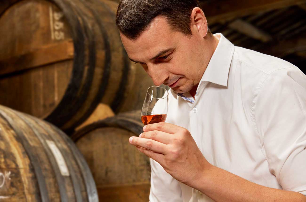 A man smells a glass of Cognac in the Remy Martin Cellar