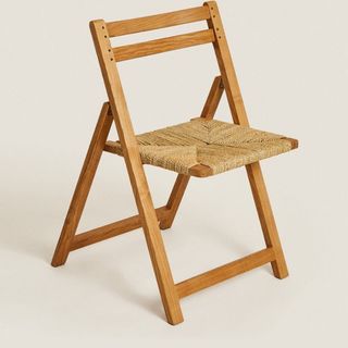 A wooden folding chair with a rattan seat design, for Zara Home's summer sale.