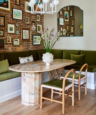 Green dining room with oval marble table and wooden and green velvet dining chairs and bench seating