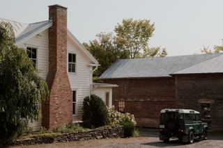 A photo of a barn alongside a white house