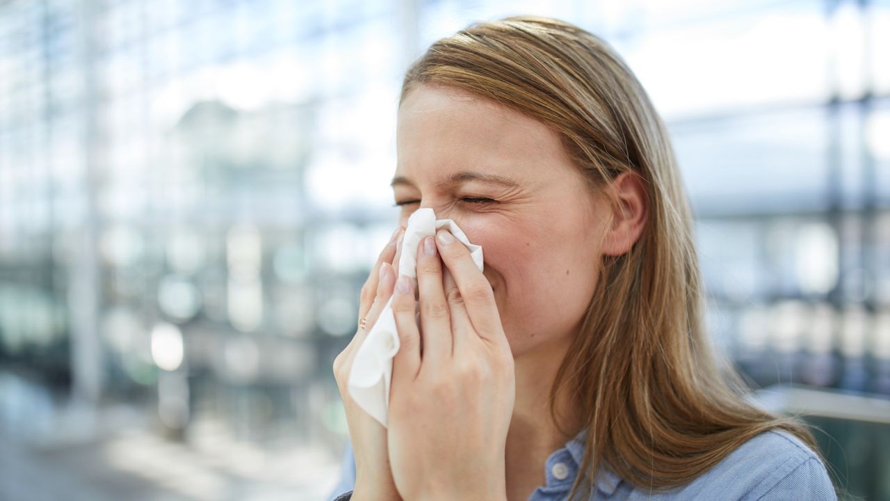 Young woman blowing nose