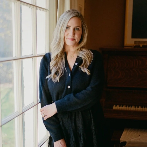 Image of a woman in a black dress standing by a window