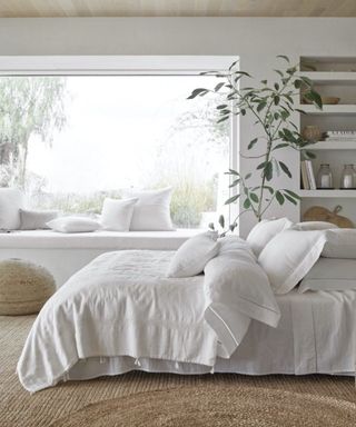 The White Company bedding on a bed beside a plant.