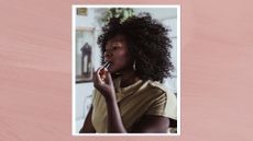 A verticle image of a woman with curly hair and wearing silver hoop earrings, applying a dark pink lip crayon to her top lip line/ in a pink, watercolour paint-style template template