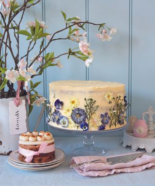 Easter cake decorated with edible flowers, and blossom stems in vintage jug