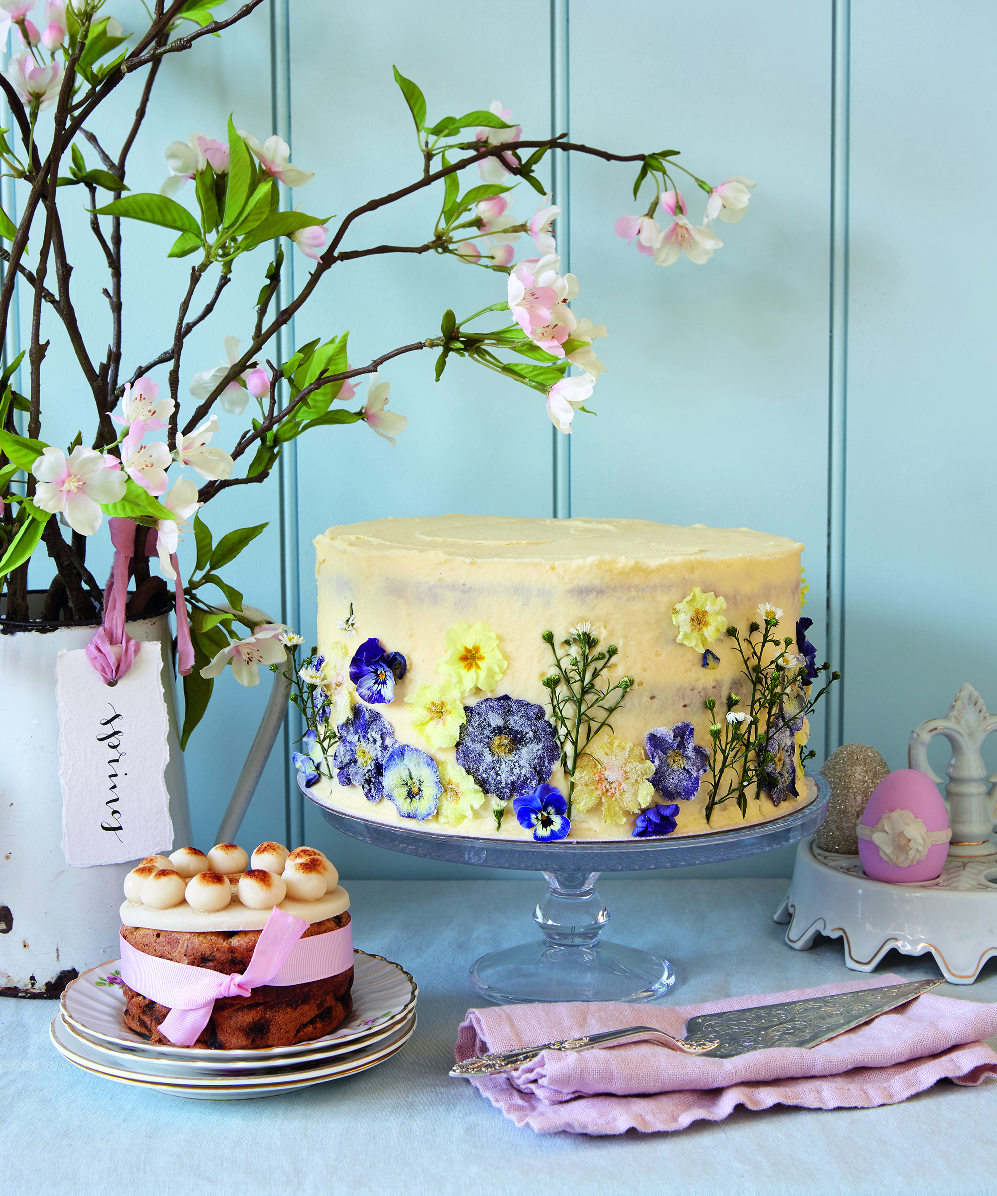 Easter cake decorated with edible flowers, and blossom stems in vintage jug