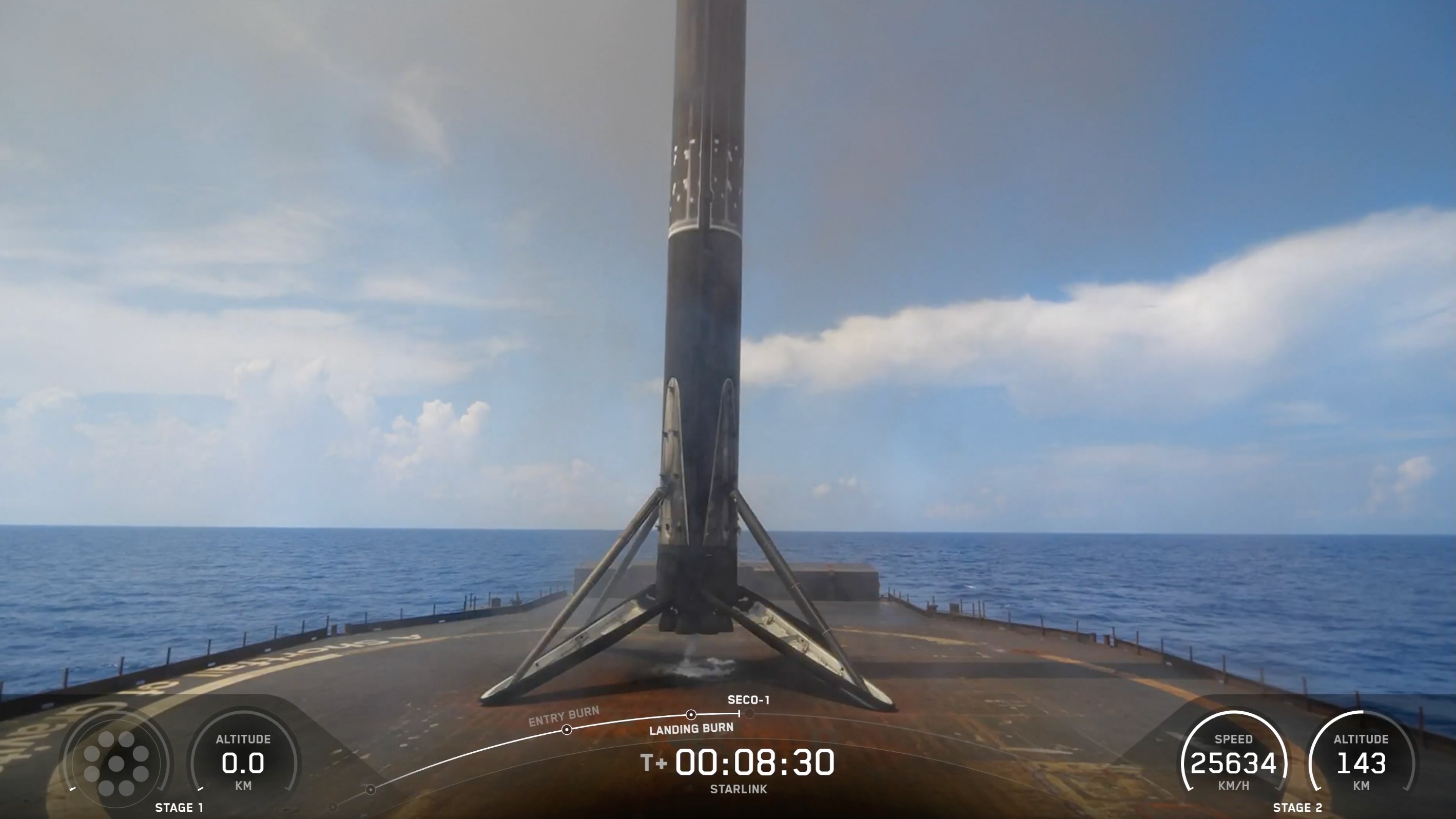 A black and white spacex falcon 9 rocket first stage sits on the deck of a ship at sea.