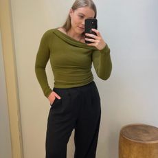 Woman wears green top and black tailored trousers