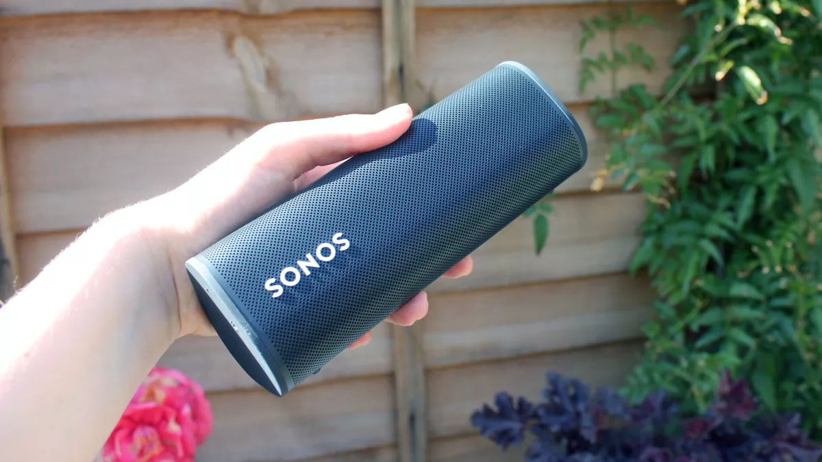 Someone holding the Sonos Roam up to the camera in a garden
