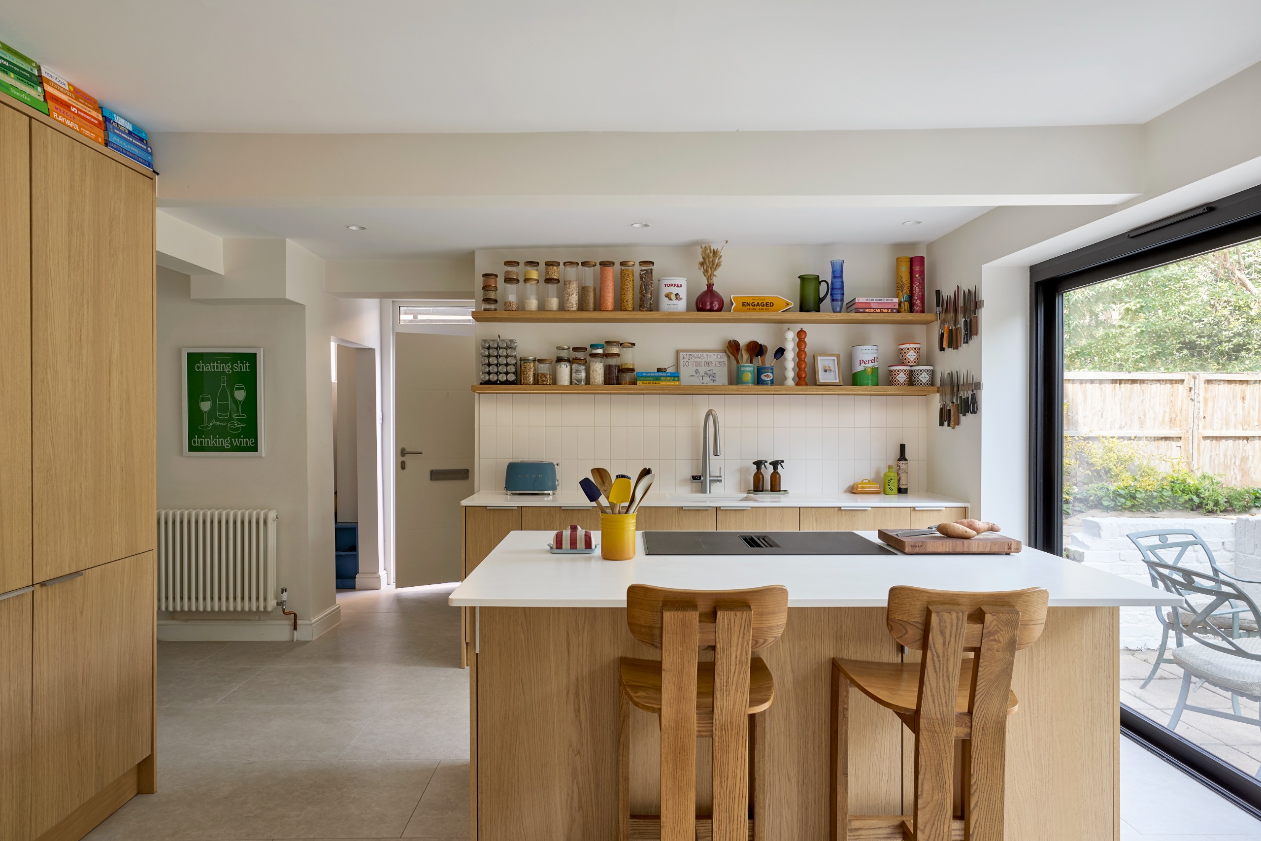 open plan kitchen with open shelving, light oak cabinets, and a hob on the island
