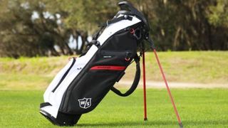 The stunning Wilson Exo Lite Stand Bag resting on the course, with its sleek black red and white colorway
