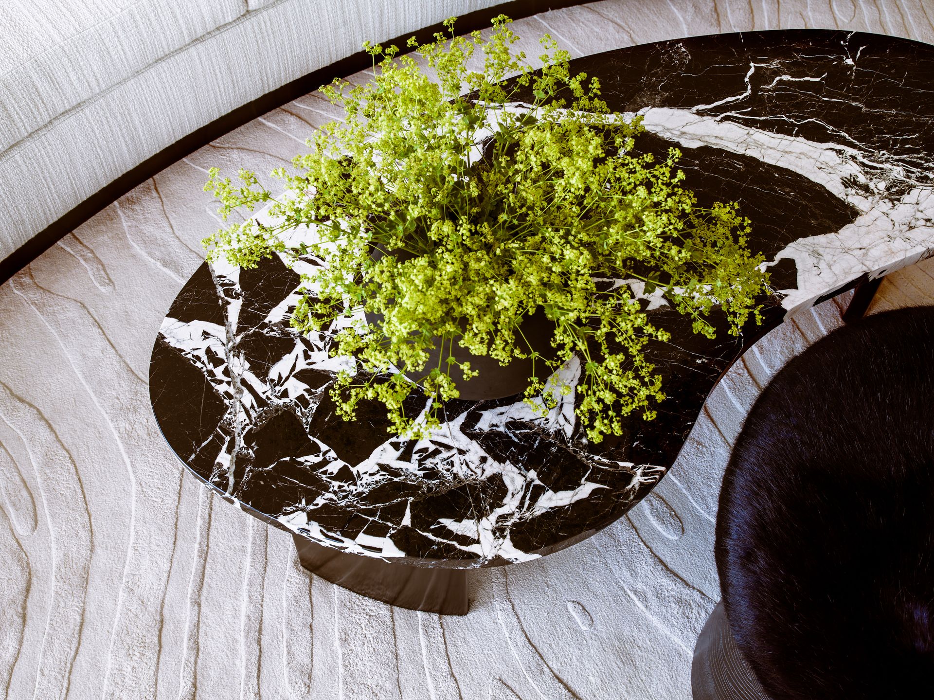 Edge of couch with textured fabric, rug and coffee table
