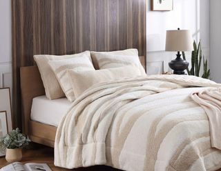 A beige bedding set on a dark wood headboard