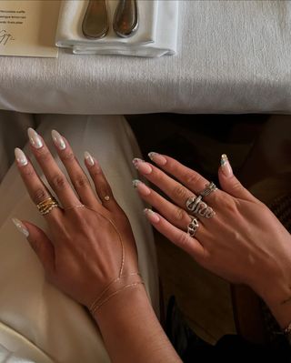 White chrome nails next to bedazzled nails