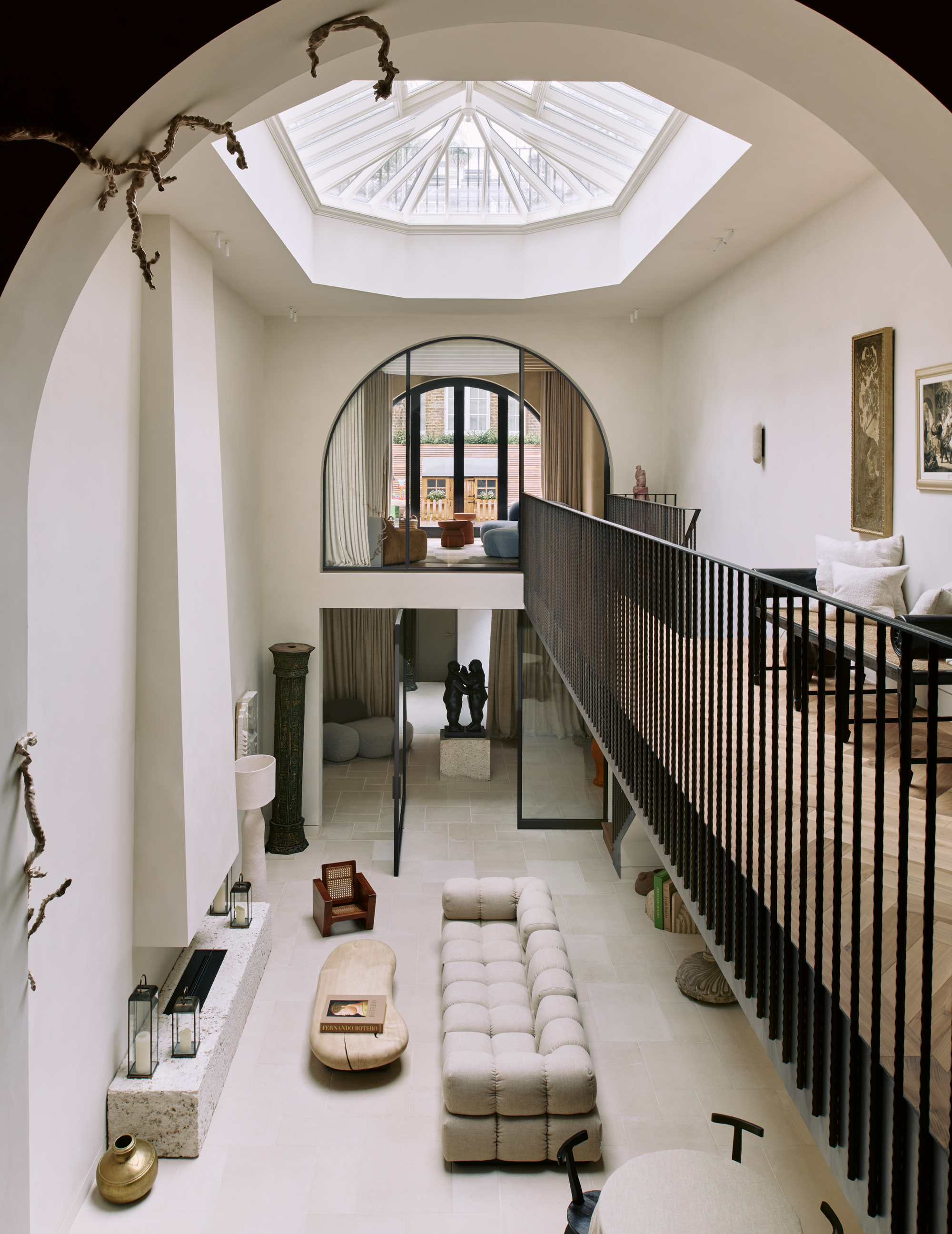 Double-story atrium that's white with black railing. There is a skylight and the downstairs has a fireplace, sofa, and coffee table.