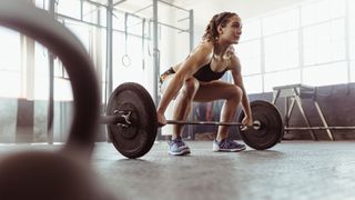 Woman performing a barbell snatch grip deadlift in the gym