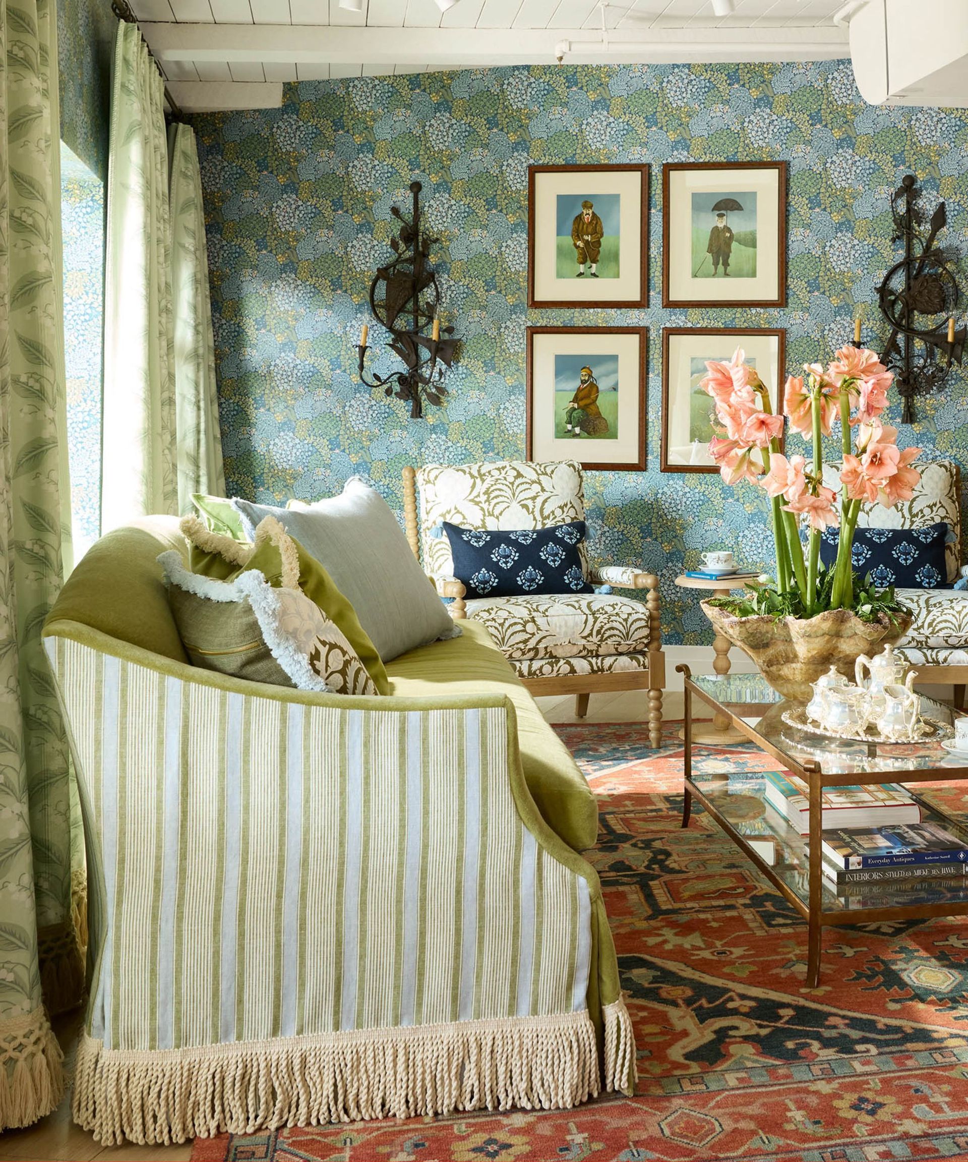 eclectic living room with a large blue and terracotta rug, a striped and fringed couch and blue floral wallpaper