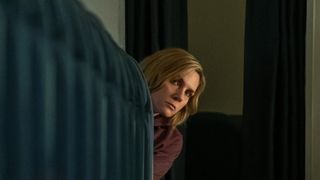 Rhea Seehorn looks suspiciously from behind a chart in Pluribus