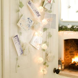 living room with white door decorated with christmas card display and fairy light