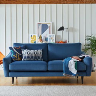 A dark blue sofa in front of a white wall