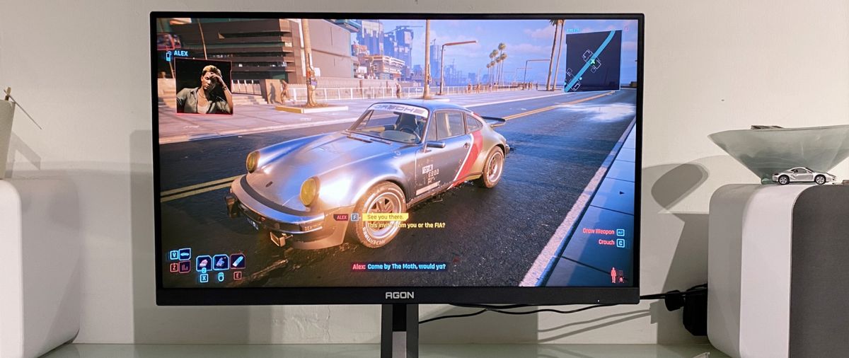 AOC Agon Pro AG276FK gaming monitor on a desk, showing Cyberpunk 2077 on screen