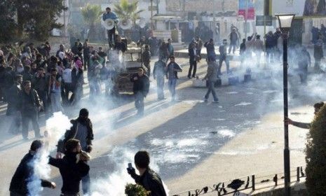 Syrian protesters cover their faces as tear gas is fired by the regime&amp;#039;s soldiers, who are continuing their crackdown despite the presence of Arab League observers.