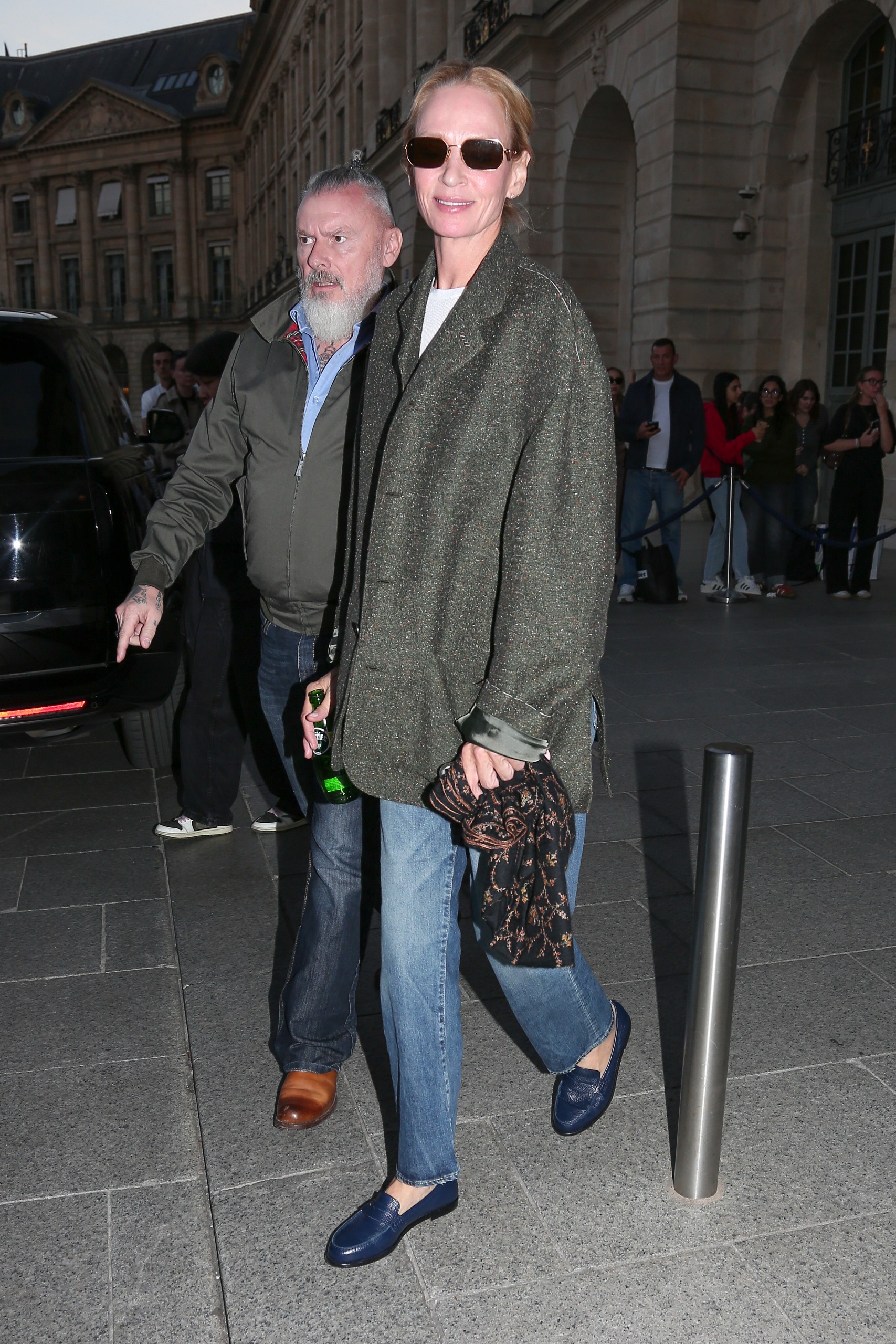 Uma Thurman steps outside in Paris wearing straight leg blue jeans with a grey blazer and navy loafers.